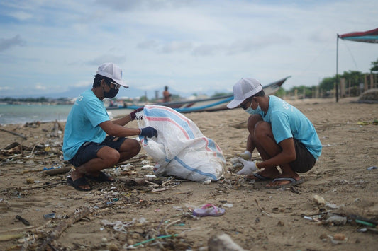Photo of people cleaning up plastic on a beach.